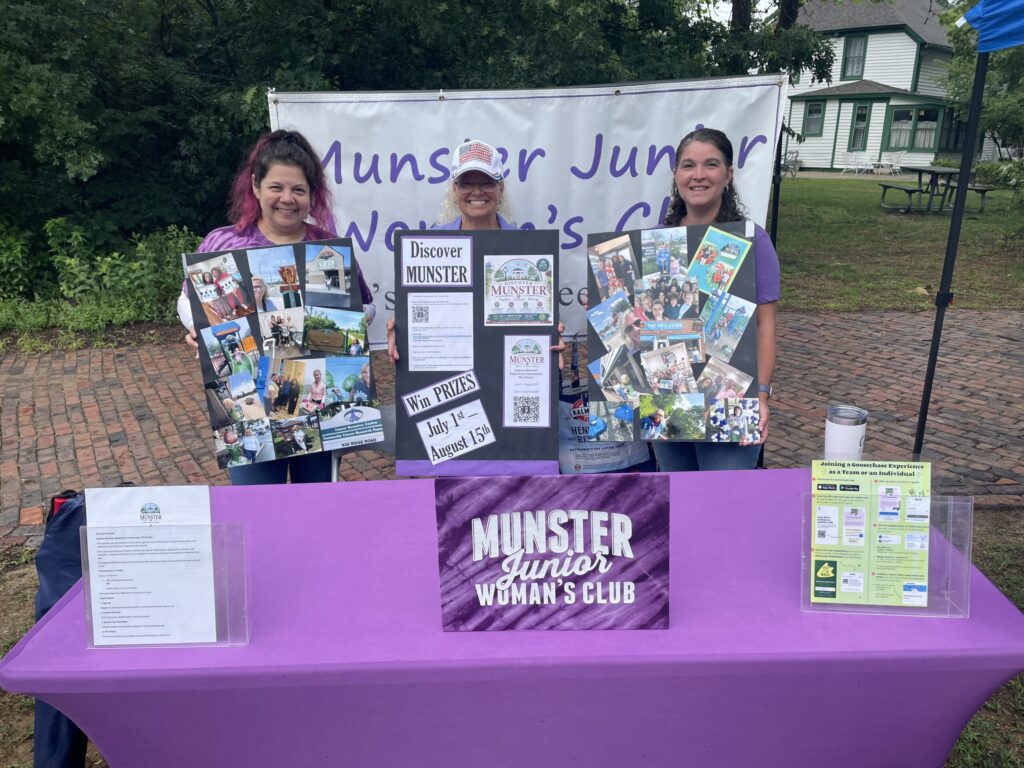 Three members of the Munster Junior Woman's Club stand behind an information table at the Munster Junior Historical Society's 250th Birthday Celebration in Heritage Park, displaying Discover Munster materials and community information.