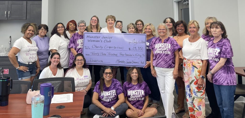 Munster Junior Woman’s Club members pose together at a donation reception holding a large check for $23,350 to charity organizations.